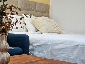1 cama con sábanas blancas y almohadas en una habitación en Villa Zoi, en Paralia Katerinis