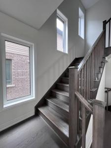Una escalera en una habitación blanca con ventana en Brand New 4 bedroom Villa by Hamilton Airport!, en Hamilton