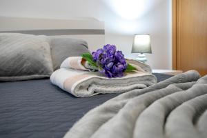uma pilha de toalhas e uma flor roxa numa cama em Casa da Belinha em Ponta Delgada