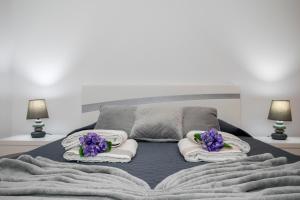 uma cama com toalhas e flores roxas em Casa da Belinha em Ponta Delgada