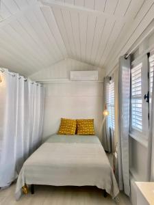 Bett in einem kleinen Zimmer mit Fenster in der Unterkunft Herbergement typique créole in Fort-de-France