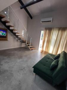 sala de estar con sofá verde y escalera en LOFTS GREEN ISLAND en Angra dos Reis