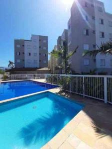 a large blue swimming pool next to a building at Apto em Ubatuba divisa com a Praia de Itagua e facil acesso as praias fica ao lado do Atacado Tenda na rodovia Rio Santos in Ubatuba