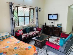 uma sala de estar com uma cama e uma televisão em Naivedyam villa em Monte Abu