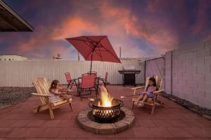 Duas raparigas sentadas em cadeiras à volta de uma fogueira. em Your Downtown Studio With All Amenities Unit B em Phoenix