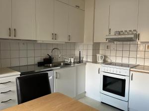 cocina con armarios blancos, fregadero y fogones en LHM en Borås