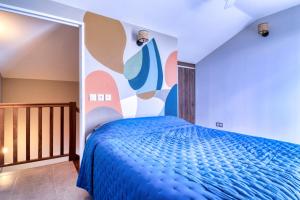 ein Schlafzimmer mit einem blauen Bett und einer farbenfrohen Wand in der Unterkunft Logement 4 pièces Étang St Paul in Saint-Paul