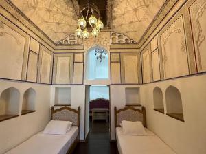 布哈拉的住宿－Marhaba boutique Madrasah 15th-16th century，配有吊灯的客房内的两张床