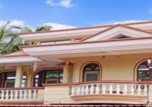 Casa amarilla grande con balcón grande en Jas Guest House, en Mobor Goa