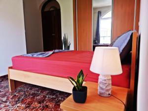 Dormitorio con cama roja con lámpara y planta en Excelente localización en Praia en Praia