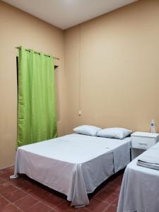 two beds in a room with a green curtain at Hostal El Amate #2 in Suchitoto