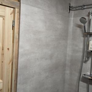 y baño con ducha y pared de hormigón. en Lapland Snow Moose en Vittangi Kapell