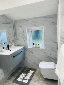 een badkamer met een wastafel, een toilet en een raam bij Luxury New Home in Kent