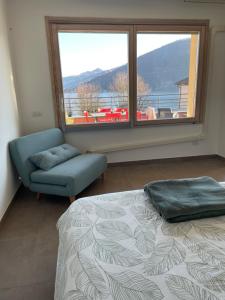 1 dormitorio con cama, sofá y ventana grande en Reflections At The Lake, en Lavena Ponte Tresa
