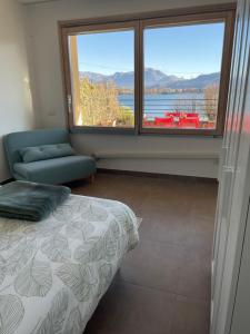 a bedroom with a bed and a large window at Reflections At The Lake in Lavena Ponte Tresa