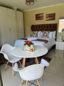 a bedroom with a bed and a white table and chairs at MorningMist Boutique Sun in Centurion +13 photos