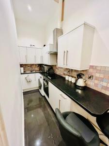 a kitchen with white cabinets and a black counter top at STYLISH 1Bhk HEART OF THE CITY in Edinburgh
