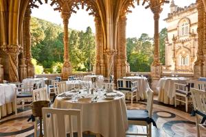 a restaurant with white tables and chairs in a building at Palace Hotel do Bussaco in Luso