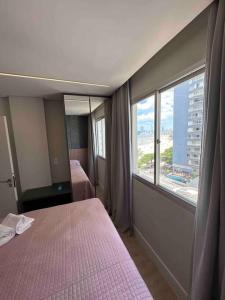 ein Hotelzimmer mit zwei Betten und einem großen Fenster in der Unterkunft Apartamento Frente Mar Bc 704 in Balneário Camboriú