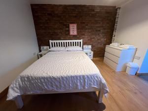 a bedroom with a bed and a brick wall at Hidden Havens in Norwich