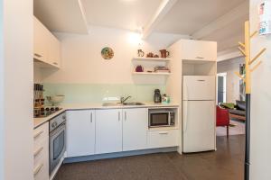 a kitchen with white cabinets and a white refrigerator at Retro Living - Lush Garden in Christchurch