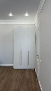an empty room with white cabinets and wood floors at Люкс Апартаменты в центре левого берега Астаны in Taldykolʼ