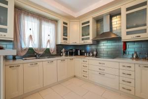 a large kitchen with white cabinets and blue tiles at Scorpios Villa in Kefallonia