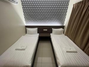two twin beds in a small room with a window at Pekan Auto City Budget Hotel in Pekan