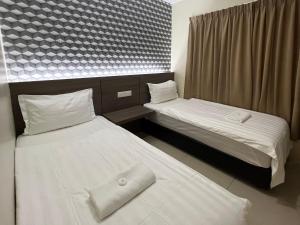 two beds in a small room with white sheets at Pekan Auto City Budget Hotel in Pekan