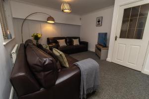 a living room with a leather couch and a television at DWELLCOME HOME Ltd Spacious 3 Double Bedroom Boldon Townhouse - see our site for assurance in Boldon