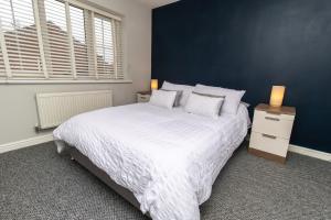 a bedroom with a large white bed and a blue wall at DWELLCOME HOME Ltd Spacious 3 Double Bedroom Boldon Townhouse - see our site for assurance in Boldon