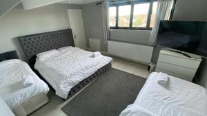 a bedroom with two beds and a flat screen tv at Large house close to Greenwich in Eltham