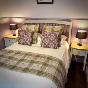 um quarto com uma cama com almofadas e 2 candeeiros em Sibton White Horse Inn em Saxmundham