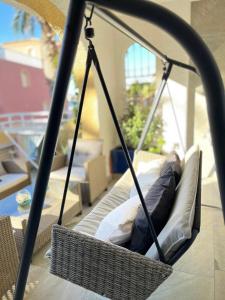 een hangende stoel met kussens in de woonkamer bij Piscis Family Bungalow La Manga in La Manga del Mar Menor