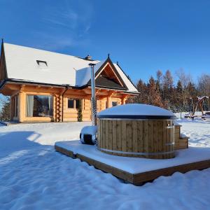 ein Blockhaus mit einem Whirlpool im Schnee in der Unterkunft beskid house in Spytkowice