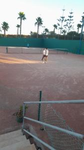 zwei Personen, die Tennis auf einem Tennisplatz spielen in der Unterkunft Marina Golf appartement de luxe in Asilah