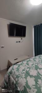a bedroom with a bed and a flat screen tv on the wall at Departamento nuevo y cómodo in Santiago