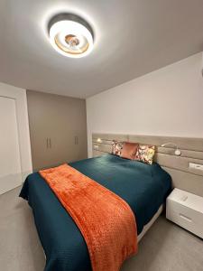 a bedroom with a large bed with an orange blanket at Sunset Apartment & Heated Pool in Los Cristianos