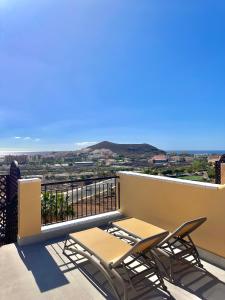 a balcony with two chairs and a view of the city at Sunset Apartment & Heated Pool in Los Cristianos