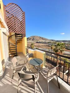 a patio with chairs and a table on a balcony at Sunset Apartment & Heated Pool in Los Cristianos
