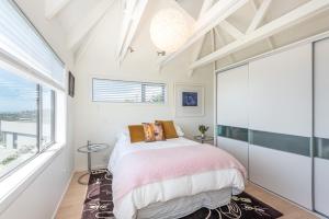 um quarto com uma cama e uma grande janela em Christchurch - Art space, sea views, private em Christchurch