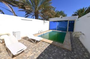 a swimming pool with two white chairs and a swimming pool at استراحة الضبيانية in AlUla