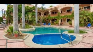 洛斯巴里勒斯的住宿－Los Barriles Hotel，棕榈树建筑前的游泳池