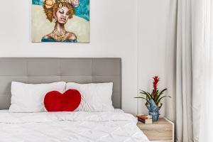 a red heart pillow sitting on top of a bed at Dodi Blue Apartament in Arad