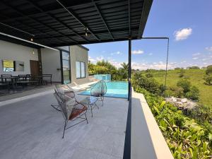 une terrasse avec une table et des chaises en verre ainsi qu'une piscine dans l'établissement Eco Hotel La Colina Mirador, à Quimbaya