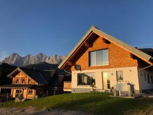 una casa en una colina con montañas en el fondo en Appartement Tannenhof III, en Ramsau am Dachstein