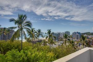 a view of the beach and palm trees from a balcony at Kalug - Mansão de Luxo com Vista Mar na Praia do Milionários in Ilhéus