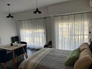 um quarto com uma cama, uma mesa e janelas em Dpto Pico Alquiler Temporario em Santa Rosa