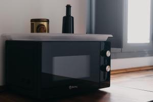 a black microwave oven with a bottle of wine on top at Casa Palacio -Sanlúcar- in Sanlúcar de Barrameda
