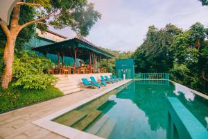 愛妮島的住宿－Unique Stays at Karuna El Nido - The Glasshaus，一座房子旁的游泳池,配有蓝色躺椅